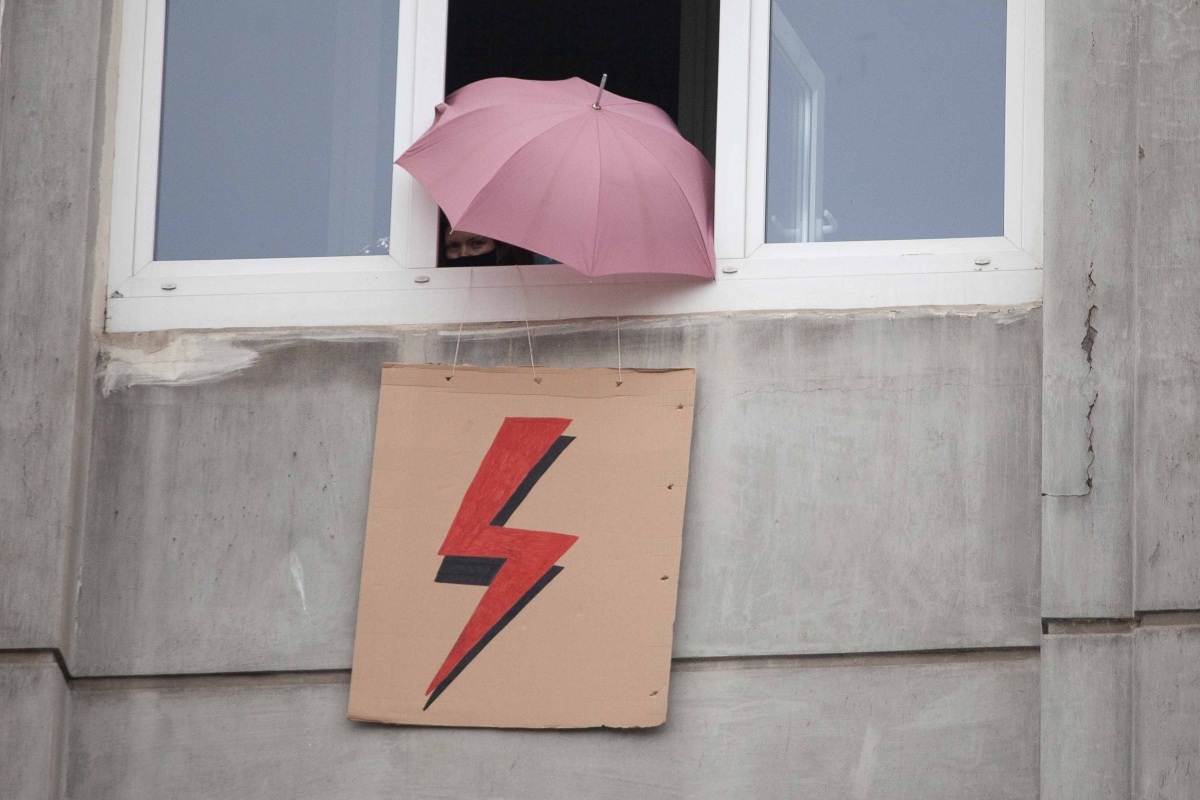Geöffnetes Fenster aus dem ein Schild mit Blitz und ein Regenschirm ragen