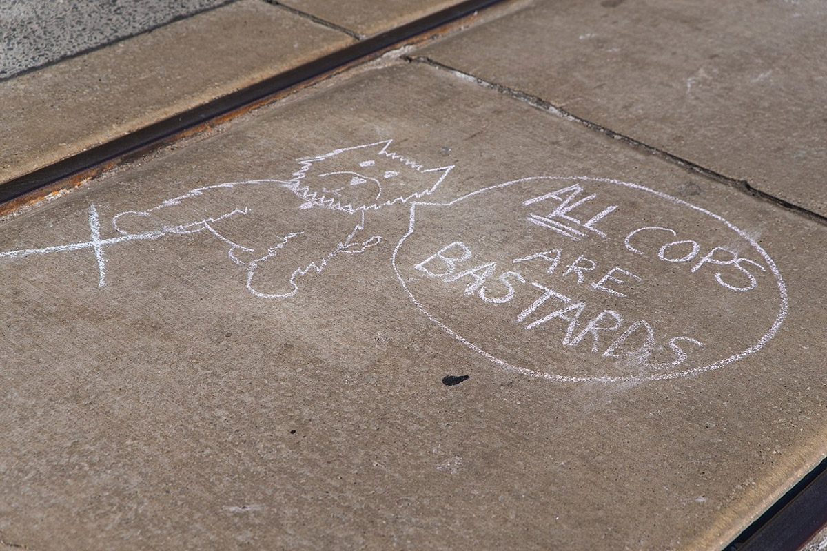 Kreidezeichnung auf Straße zeigt einen Hund mit Sprechblase: All Cops Are Bastards