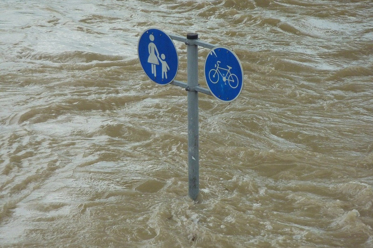 Schild mit Zeichen für Fußgänger und Fahrradfahrer ragt aus Hochwasser
