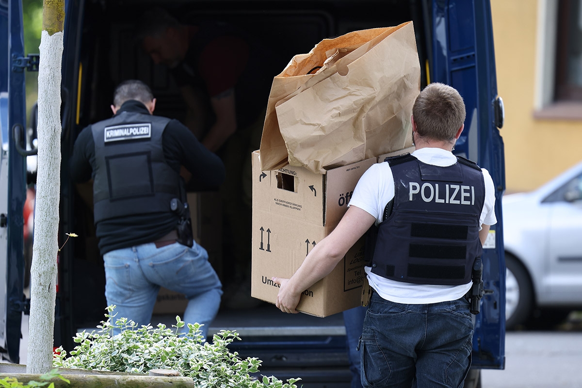  Polizisten tragen Gegenstände aus dem Wohnhaus des Tatverdächtigen