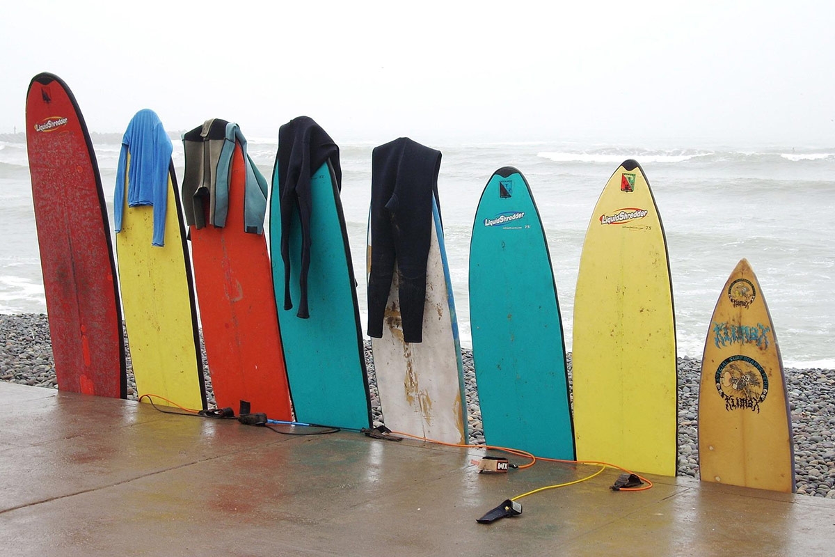 Aufgereihte Surfbretter mit Meer im Hintergrund