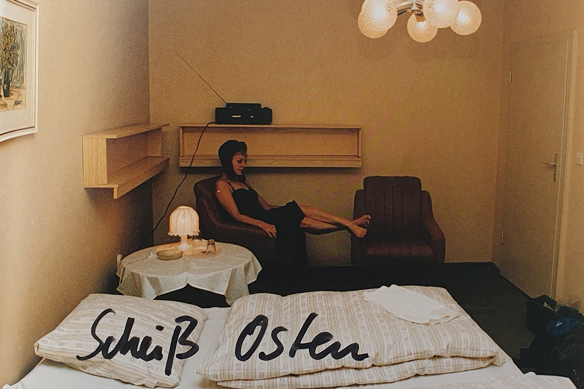 Foto einer Frau in einem Hotelzimmer, beschriftet mit »Scheiß-Osten«
