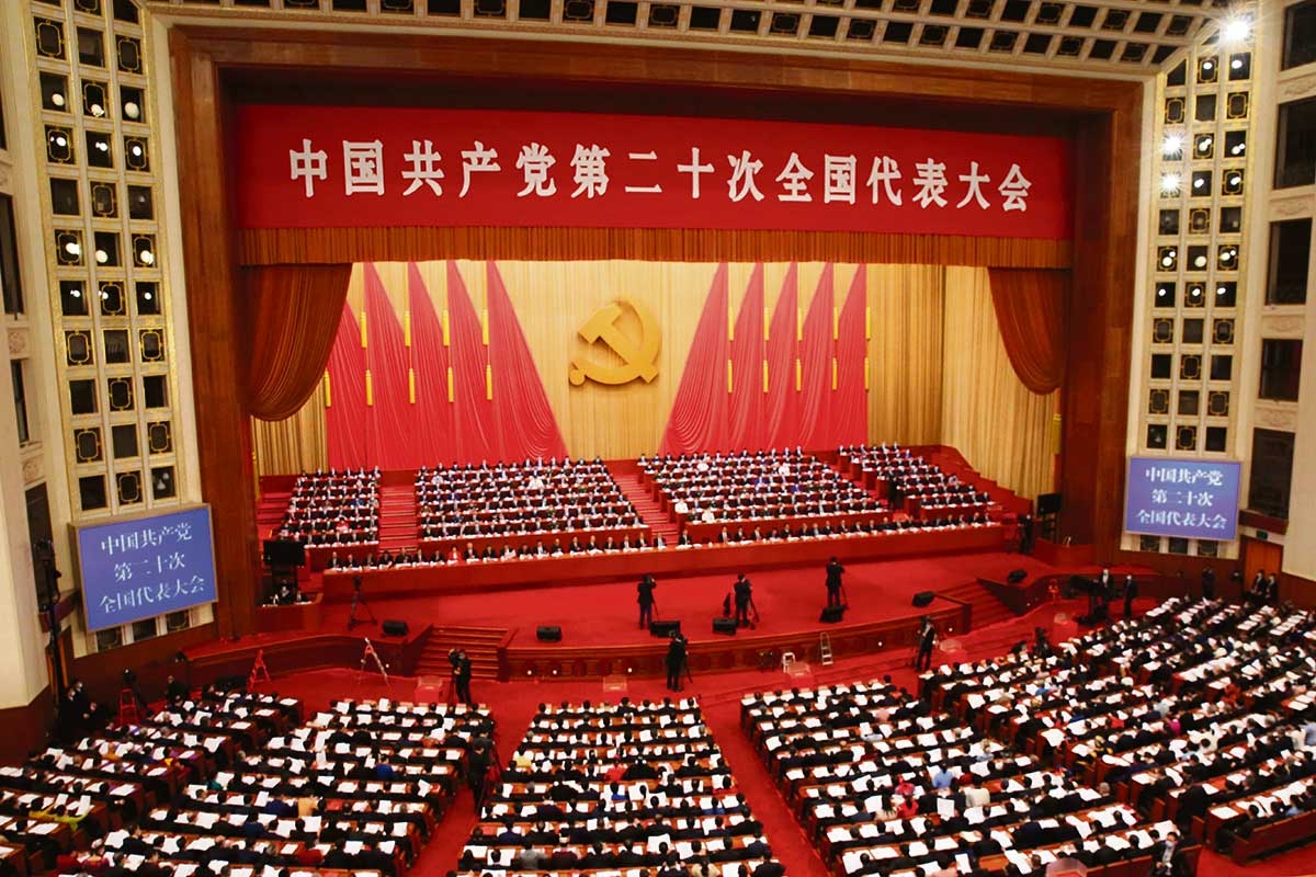 Ein mit roten Fahnen geschmückter Konferenzsaal voller Menschen