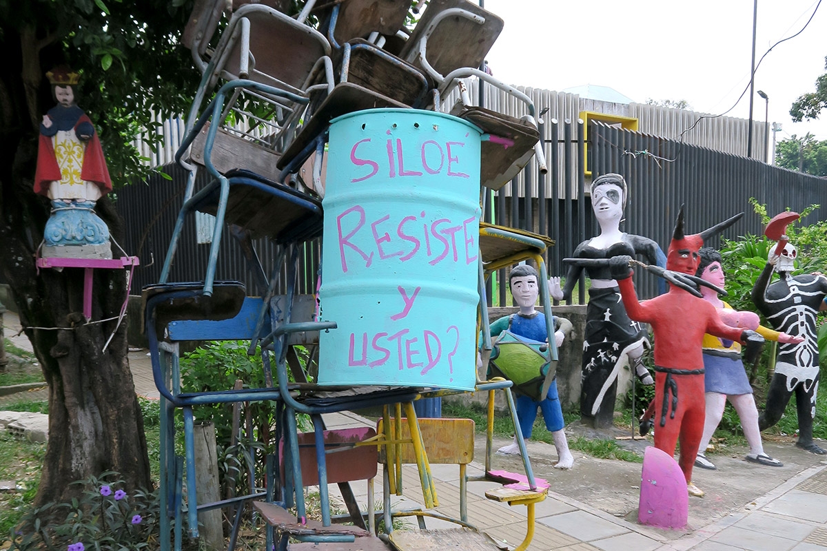 eine Skulptur aus Stühlen und einem Ölfass mit der Aufschrift "Siloe resiste - y usted?"