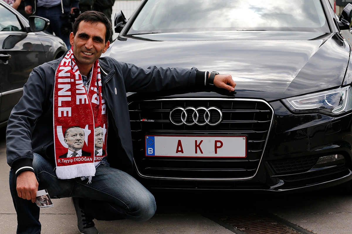 Ein Mann posiert vor einem Auto mit Nummernschild "AKP"