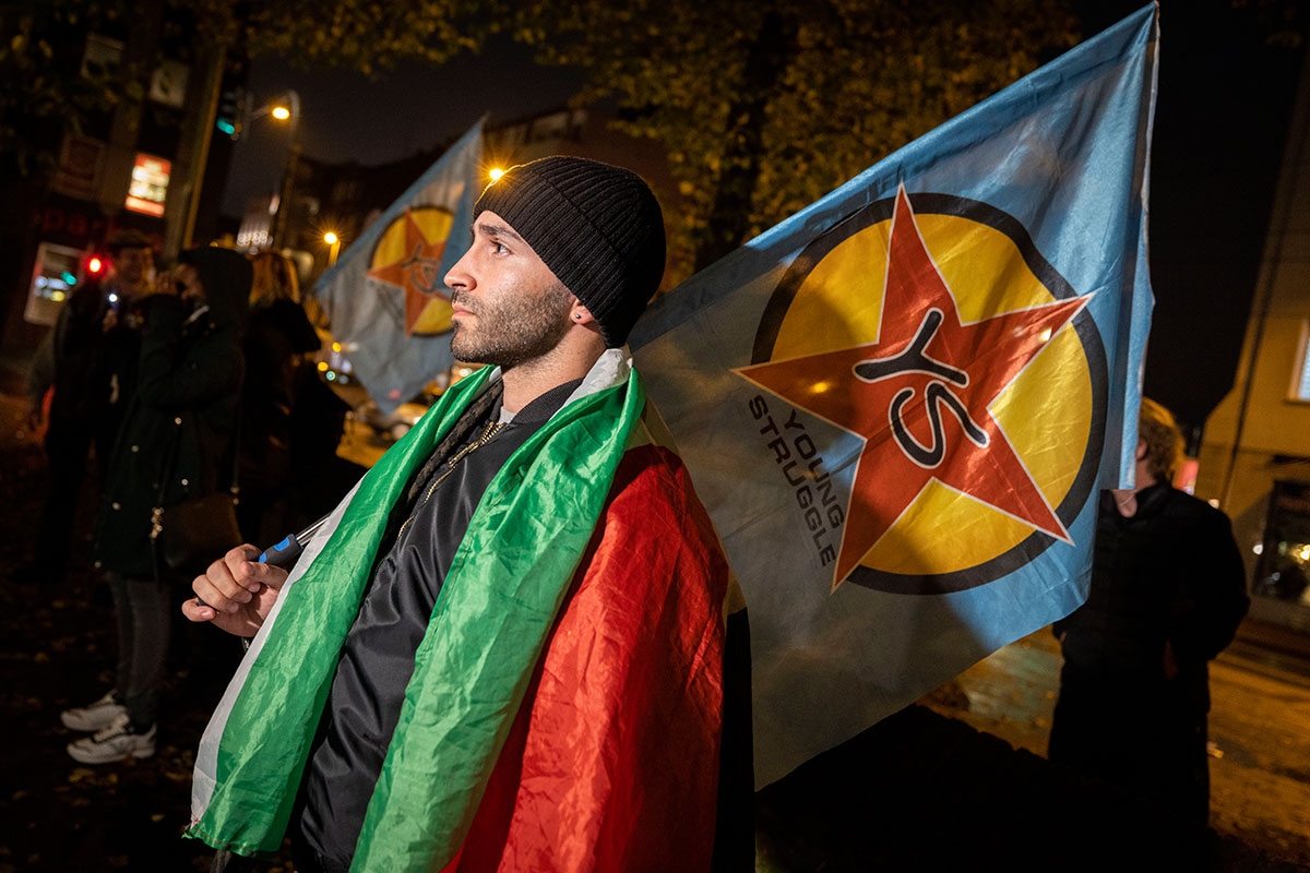 Ein Mann mit Fahne von Young Struggle und einer Palästinenser-Fahne auf den Schultern, bei einer Kundgebung in Duisburg am 12. Oktober