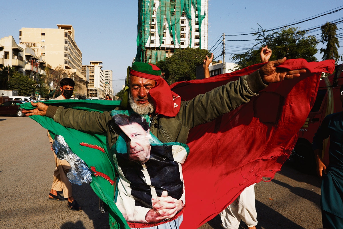 Dem Idol verbunden. Ein Anhänger der PTI mit Imran Khans Porträt und Parteifahne tanzt in Karatschi, 11. Februar
