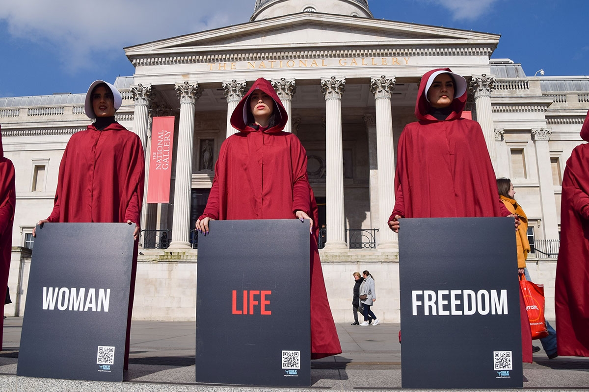 Frauen, in roten Roben im Stile von »The Handmaid's Tale«, protestieren auf dem Londoner Trafalgar Square mit Schildern »Woman - Life - Freedom«