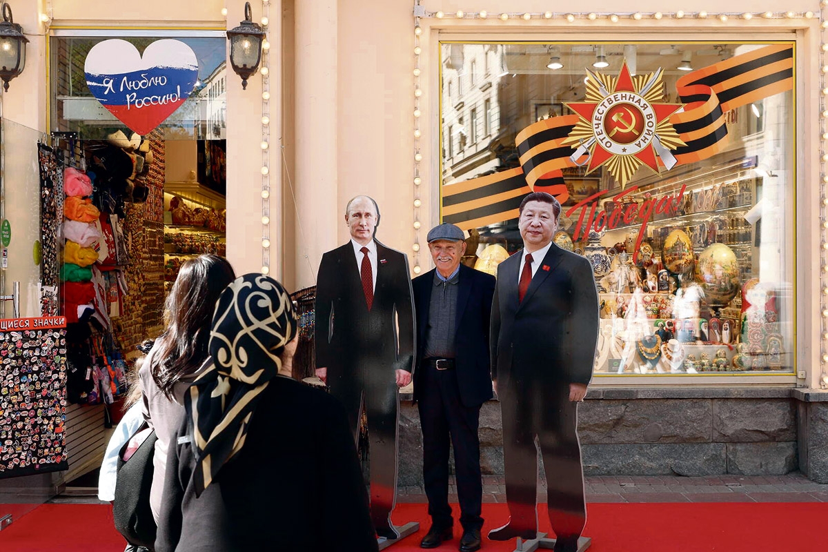 Fanfoto mit den Pappkameraden. Ein Passant auf dem Arbat in Moskau zwischen Aufstellern von Wladimir Putin und Xi Jinping, 29. April