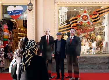 Fanfoto mit den Pappkameraden. Ein Passant auf dem Arbat in Moskau zwischen Aufstellern von Wladimir Putin und Xi Jinping, 29. April