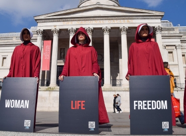 Frauen, in roten Roben im Stile von »The Handmaid's Tale«, protestieren auf dem Londoner Trafalgar Square mit Schildern »Woman - Life - Freedom«