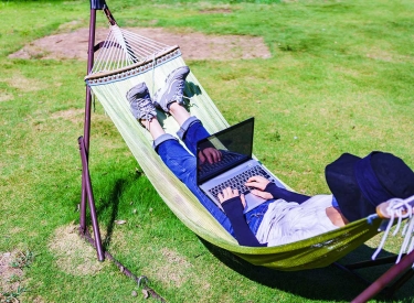 Mensch mit Laptop in Hängematte