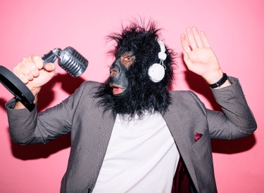 Person mit Gorilla-Maske spricht in ein Mikrofon