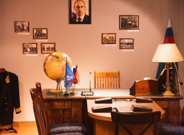 Schreibtisch mit Fahnen und gerahmten Bildern im Hintergrund