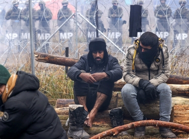 Migranten nahe Grodno, im Hintergrund polnische Grenzschütze
