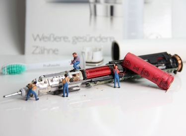 Miniaturfiguren reparieren eine elektronische Zahnbürste