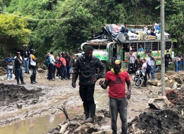 Buspassagiere bahnen sich nach einem Erdrutsch ihren Weg durch den Schlamm