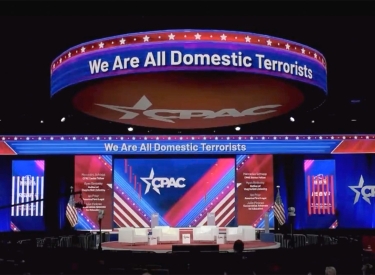 Bühne bei einem Treffen der CPAC mit dem Lichtschriftzug We are all Domestic Terrorists