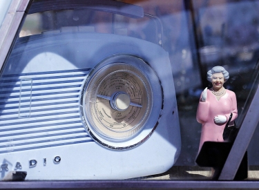 Figur der Queen neben einem antiken Radio in einem Auto