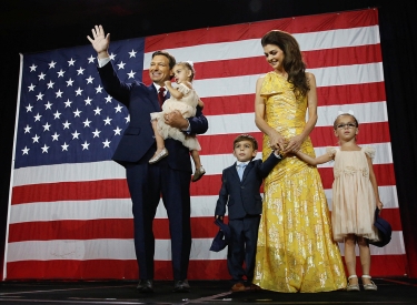Ron DeSantis winkend mit Ehefrau und Kindern vor USA-Flagge