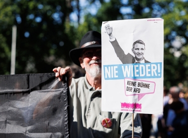 Ein Gegendemonstrant hält ein Schild mit der Aufschrift "Nie wieder! Keine Bühne der AfD" und einem Bild von Björn Höcke (AfD)